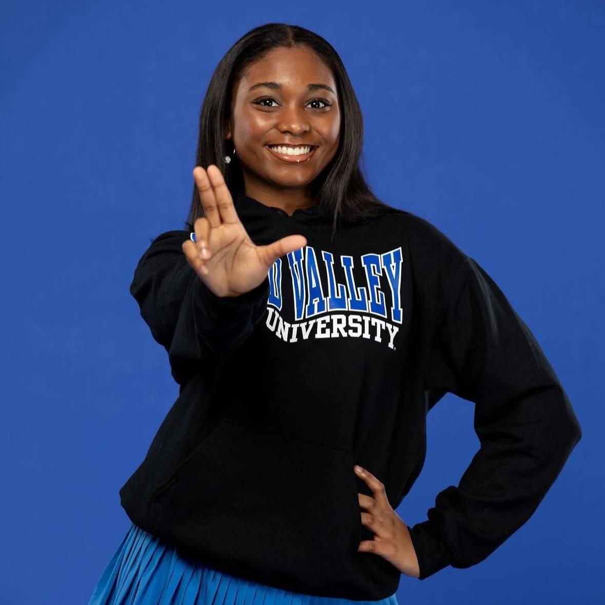 student wearing GVSU gear showing the anchor-up sign